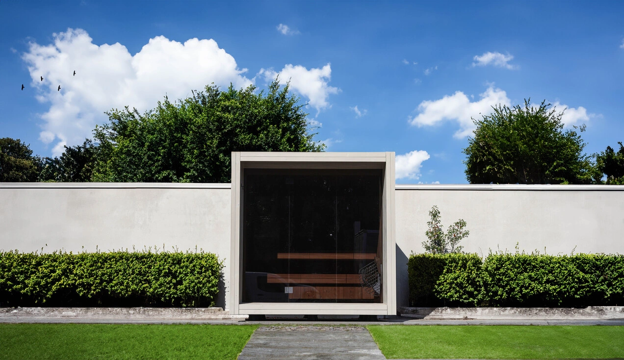 Luxe kubusvormige design buitensauna met glazen voorwand en moderne thermowood afwerking, in de tuin voor een ultieme outdoor wellness ervaring.