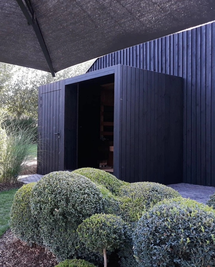 Luxe kubusvormige design buitensauna met berging, glazen voorwand en moderne thermowood afwerking, in de tuin voor een ultieme outdoor wellness ervaring.
