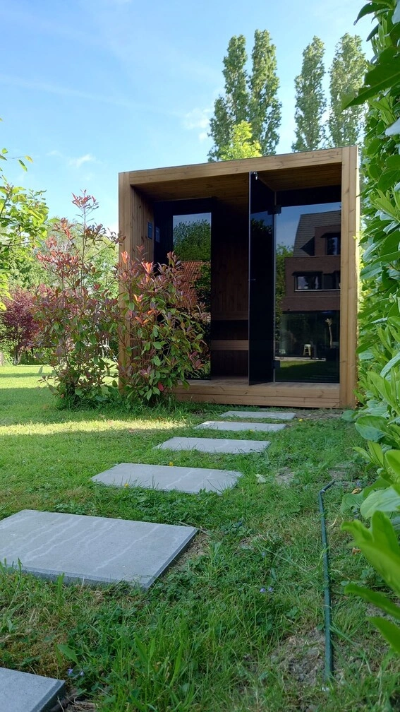 Luxe kubusvormige design buitensauna met glazen voorwand en moderne thermowood afwerking, in de tuin voor een ultieme outdoor wellness ervaring.