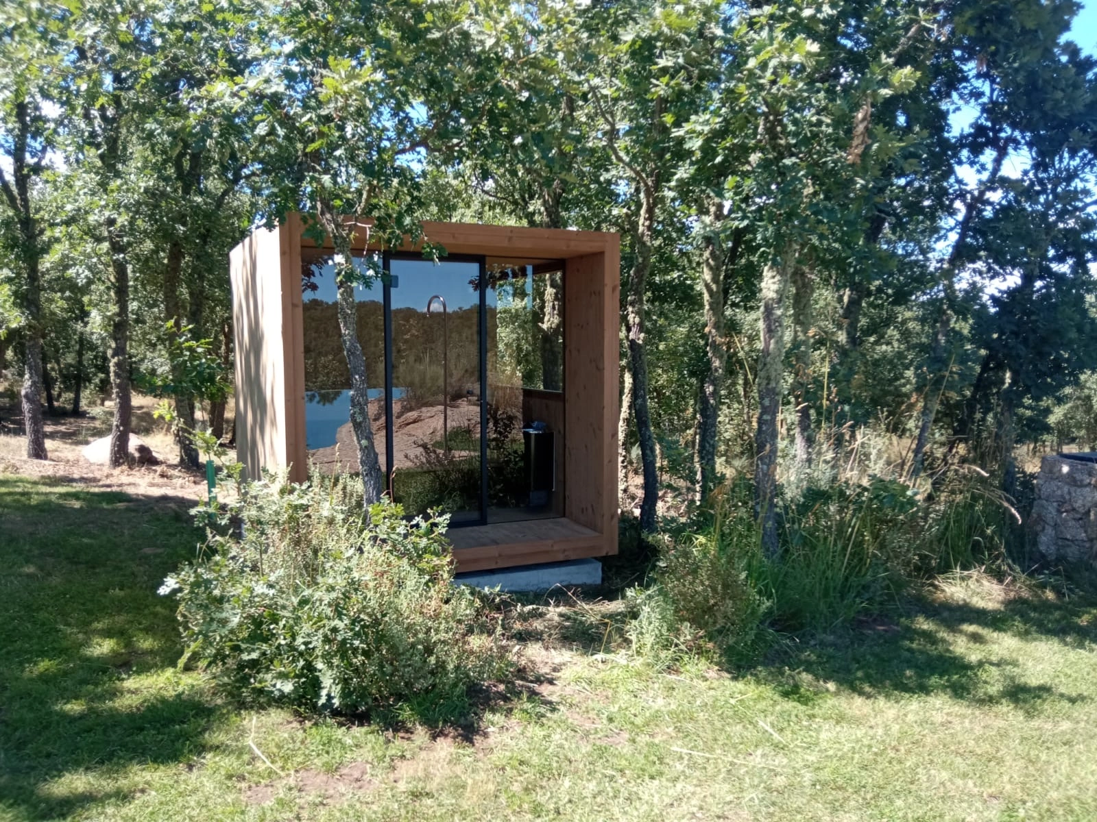 Luxe kubusvormige design buitensauna met infrarood glazen voorwand en moderne thermowood afwerking, in de tuin voor een ultieme outdoor wellness ervaring.