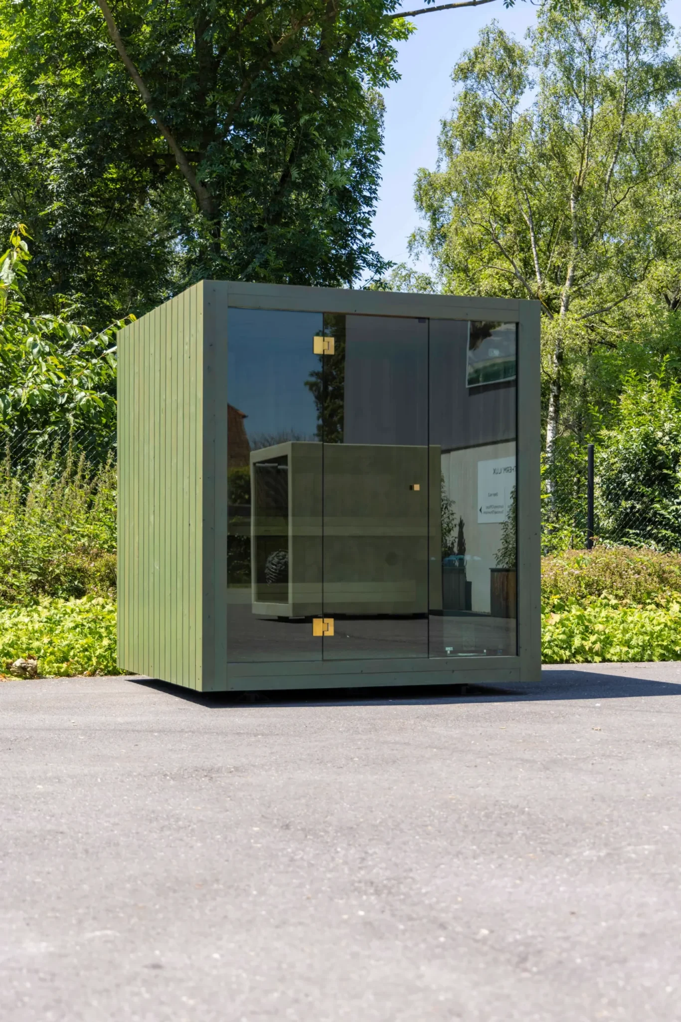 Luxe kubusvormige design buitensauna met glazen voorwand en moderne thermowood afwerking, in de tuin voor een ultieme outdoor wellness ervaring.
