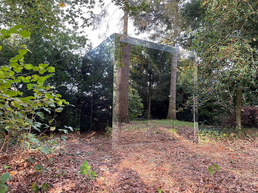 Luxe kubusvormige design buitensauna met moderne spiegelglasafwerking, in de tuin voor een ultieme outdoor wellness ervaring.