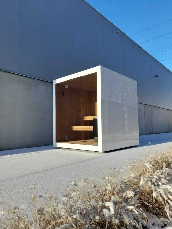 Luxe kubusvormige design buitensauna met glazen voorwand en moderne aluminium afwerking, in de tuin voor een ultieme outdoor wellness ervaring.