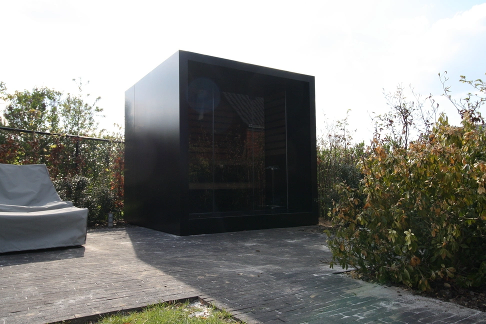 Luxe kubusvormige design buitensauna met glazen voorwand en moderne aluminium afwerking, in de tuin voor een ultieme outdoor wellness ervaring.
