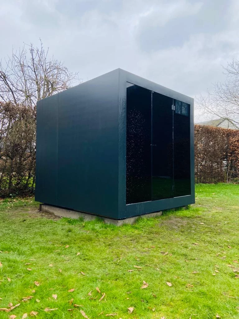 Luxe kubusvormige design buitensauna met glazen voorwand en moderne aluminium afwerking, in de tuin voor een ultieme outdoor wellness ervaring.