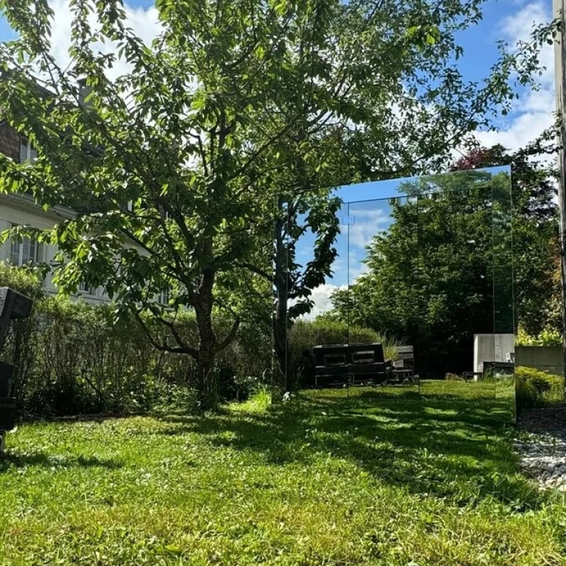 Luxuriöse würfelförmige Design-Außensauna mit moderner Spiegelfront, im Garten für ein ultimatives Outdoor-Wellness-Erlebnis.