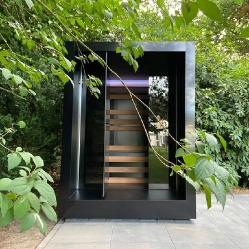 Luxe kubusvormige design compacte buitensauna met infrarood, glazen voorwand en moderne aluminium afwerking, in de tuin voor een ultieme outdoor wellness ervaring.