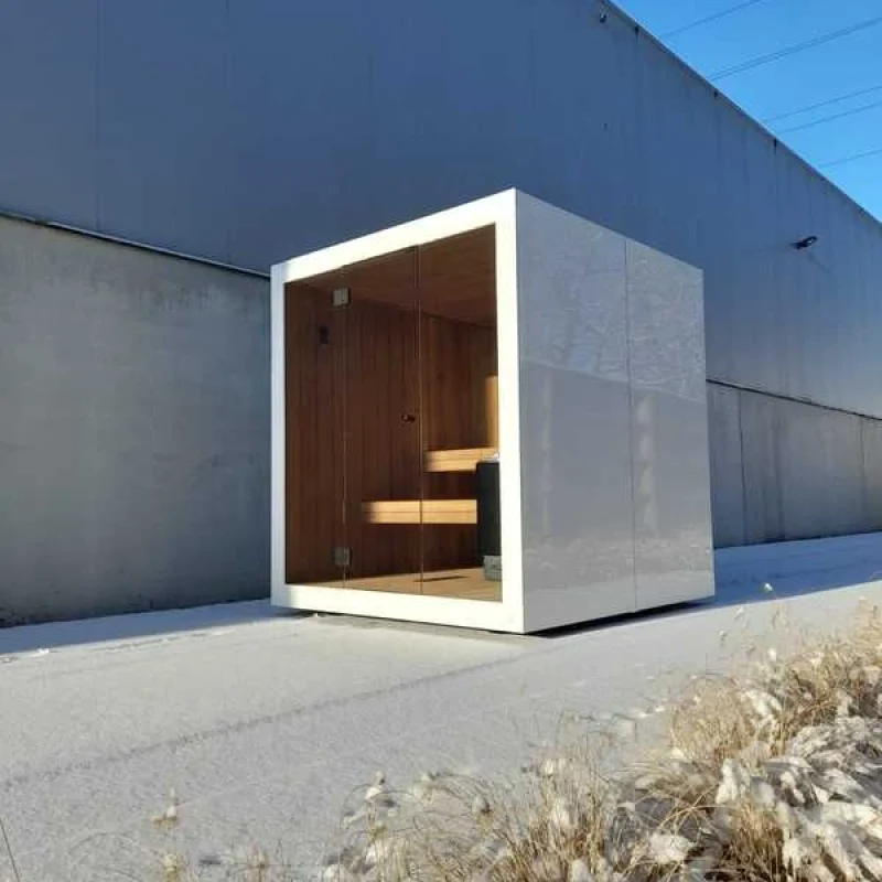 Luxury cube-shaped design outdoor sauna with glass front and modern aluminium finish, in the garden for the ultimate outdoor wellness experience