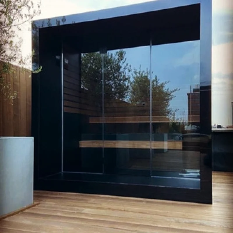 Luxury cube-shaped design outdoor sauna with glass front and modern aluminium finish, in the garden for the ultimate outdoor wellness experience.