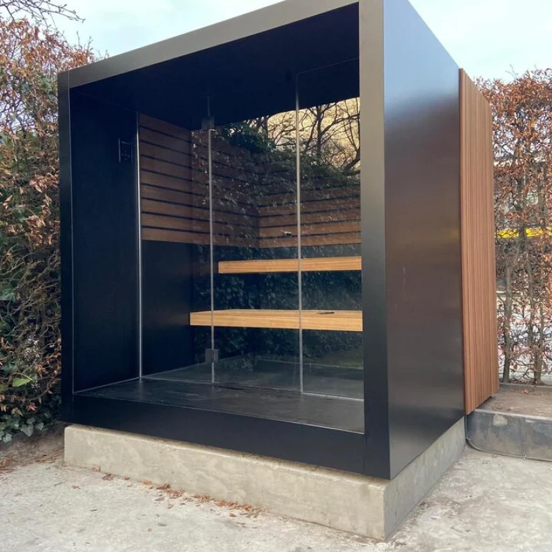 Luxury cube-shaped design outdoor sauna with glass front and modern aluminium finish, in the garden for the ultimate outdoor wellness experience.