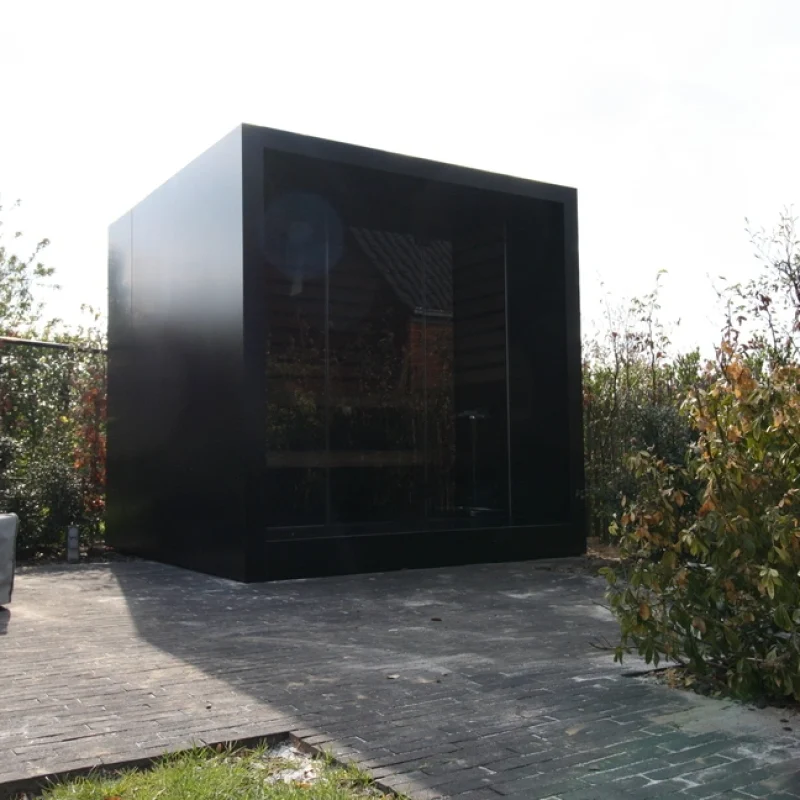 Sauna extérieur de luxe en forme de cube avec façade en verre et finition moderne en aluminium, dans le jardin pour une expérience de bien-être en plein air ultime.