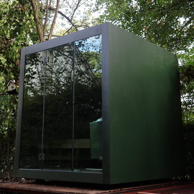 Sauna extérieur de luxe en forme de cube avec façade en verre et finition moderne en aluminium, dans le jardin pour une expérience de bien-être en plein air ultime.