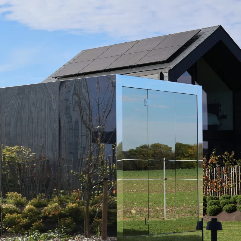 Luxe kubusvormige design buitensauna met moderne spiegelglasafwerking, in de tuin voor een ultieme outdoor wellness ervaring.