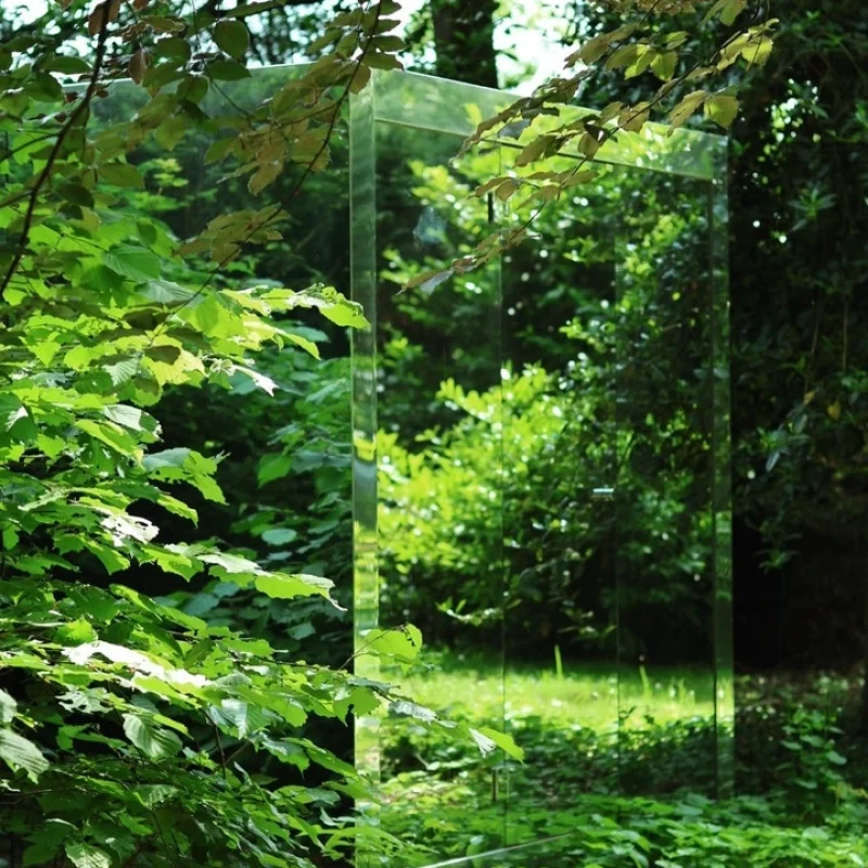 Sauna extérieur de luxe en forme de cube avec finition en verre miroir moderne, dans le jardin pour une expérience de bien-être en plein air ultime.